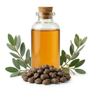 Glass bottle of bakuchi oil with cork, surrounded by seeds and green leaves on white background