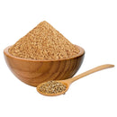 Cumin seed powder in a wooden bowl with whole cumin seeds in a wooden spoon, isolated on white background.