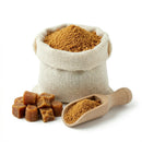 Jaggery powder bulk pack in burlap sack with cubes and wooden scoop on white background