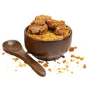 Wooden bowl filled with jaggery powder and chunks, with a wooden spoon on white background
