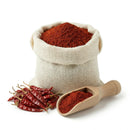 Bulk sack of red chilli powder with scoop and dried red chilies on white background
