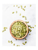 Bowl of raw pumpkin seeds on a white background with seeds scattered around